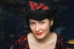 Tara O'Grady press photo in a black dress with red cherries