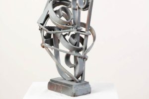 Gray metal sculpture of swirls on a white pedestal