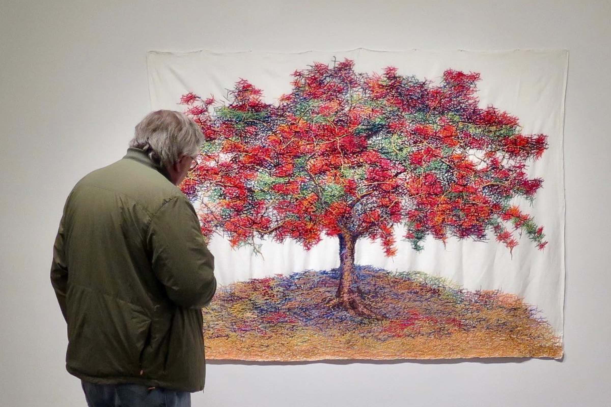 Man looking at a work of art on the wall of a tree