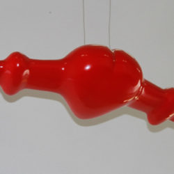 Red, glossy sculpture of an airplane that has a heart for the body of the plane