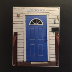 Photo of a blue door on a white house with sign above it reading "love shack"