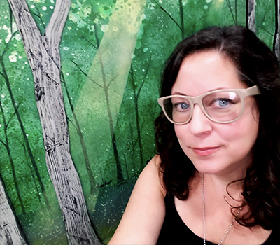 color head shot of artist in residence Lisa Watson with green forest artwork background