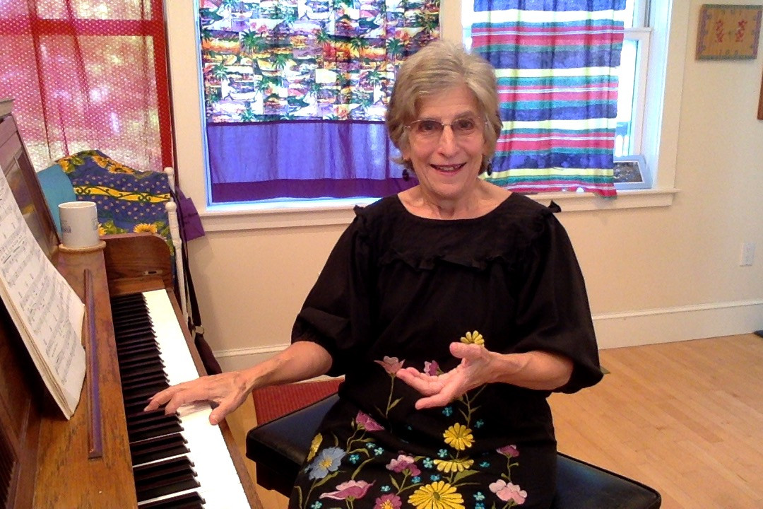 Color photo of musician instructor Nancy 3 Hoffman sitting at a piano