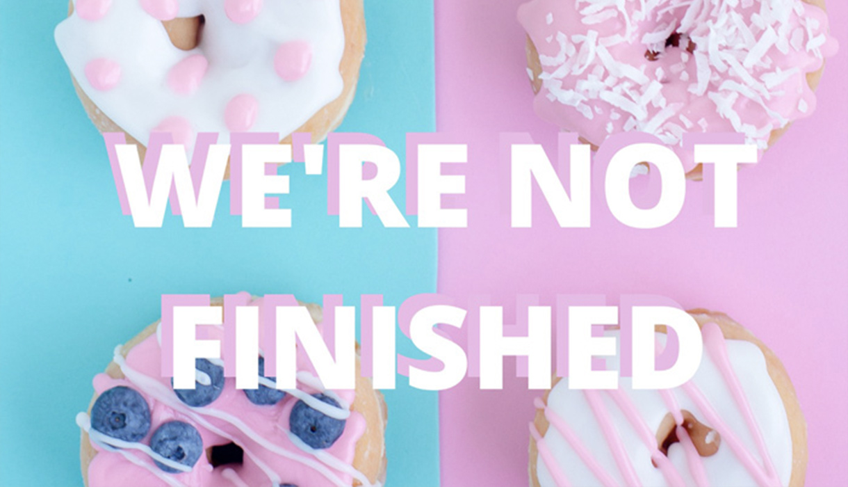 Pink frosted donuts on pink and blue background with "We're not Finished" in white cap letters