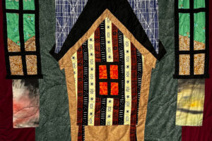 Hand-stitched quilt of a yellow house.