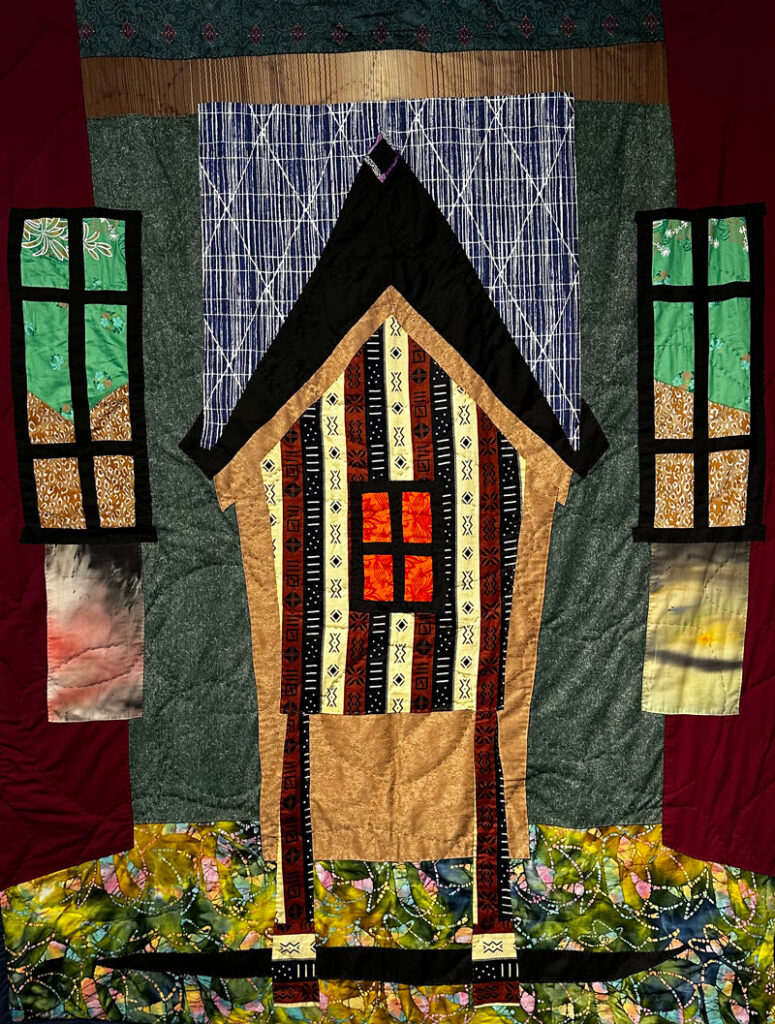 Hand-stitched quilt of a yellow house.