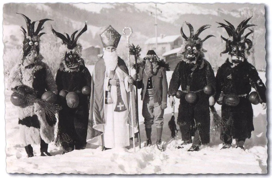 Six characters standing in a row with scary masks. One in the middle is vintage Christkindl santa in white holding a tall walking stick.