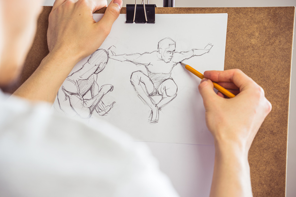 Image of a drawing board and a person sketching a leaping figure with a pencil