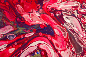 Paint pouring canvas with reds, whites and bubbles.