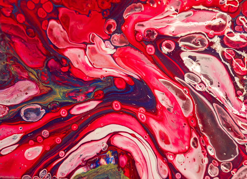 Paint pouring canvas with reds, whites and bubbles.