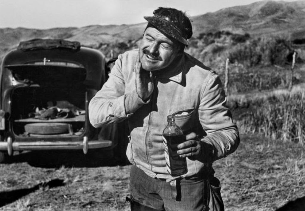 Black and white photograph of Ernest Hemingway rubbing alcohol on his chin by Robert Capa