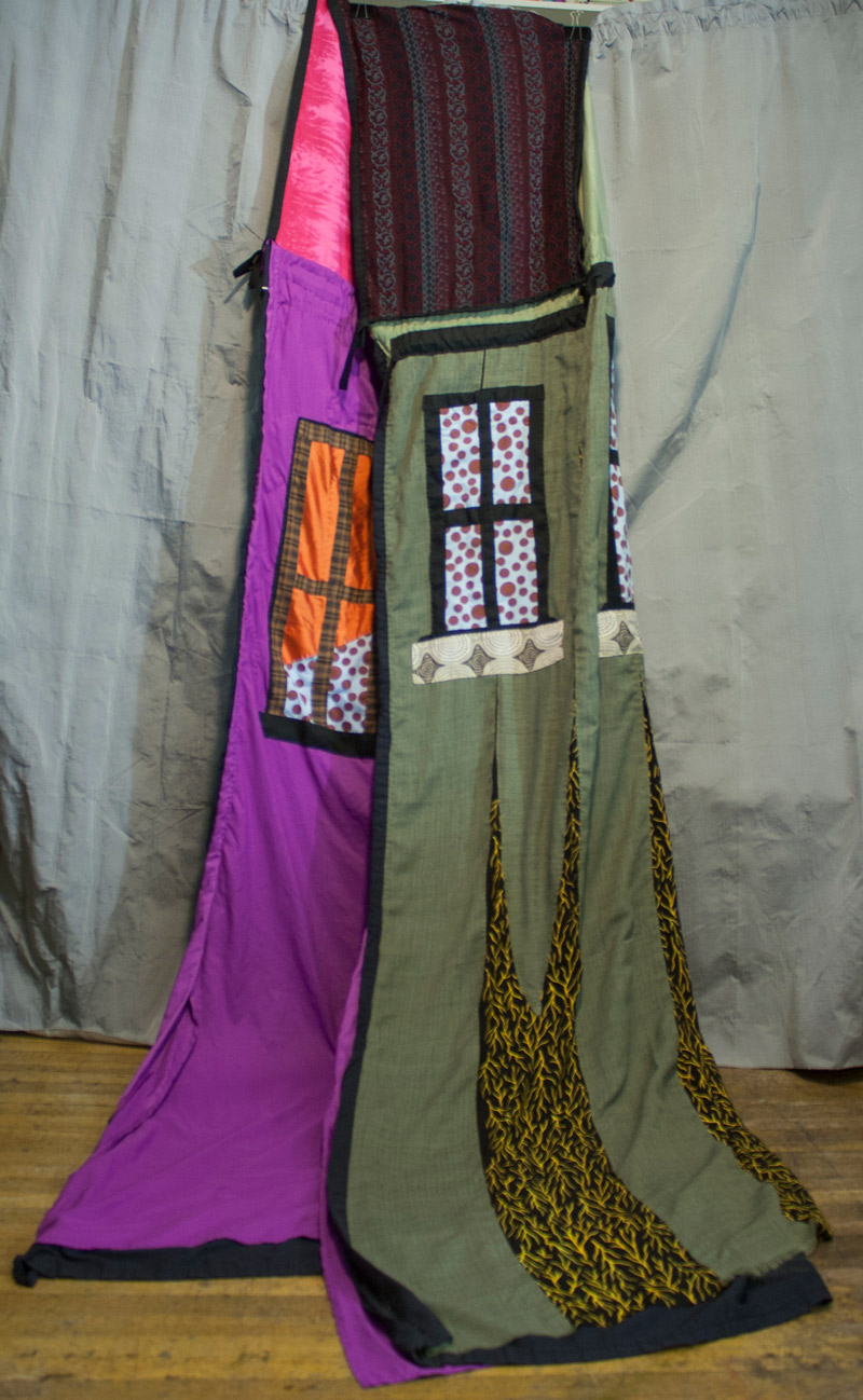 Quilt with purple inside and forest green outside, with windows sewn in fabric to mimic a house.