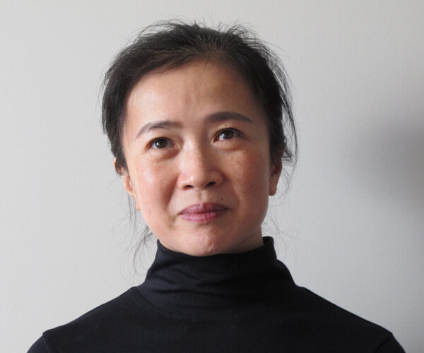 Feng-photo Author Linda Rui Feng in a black turtleneck, looking slightly upward with a thoughtful expression, photographed against a neutral gray background.