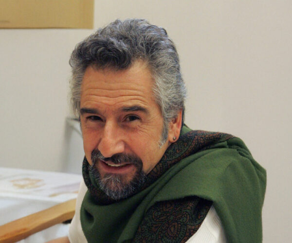 fortunado Author Peter Fortunato wearing a green scarf draped over his shoulder, smiling at the camera indoors.