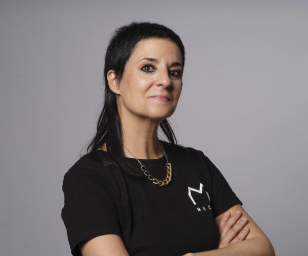foto Gemma Ruiz Palà - © Jordi Bernabé Author Gemma Ruiz Palà poses confidently in a studio portrait, dressed in black with a short gold necklace, her arms crossed and gaze steady.