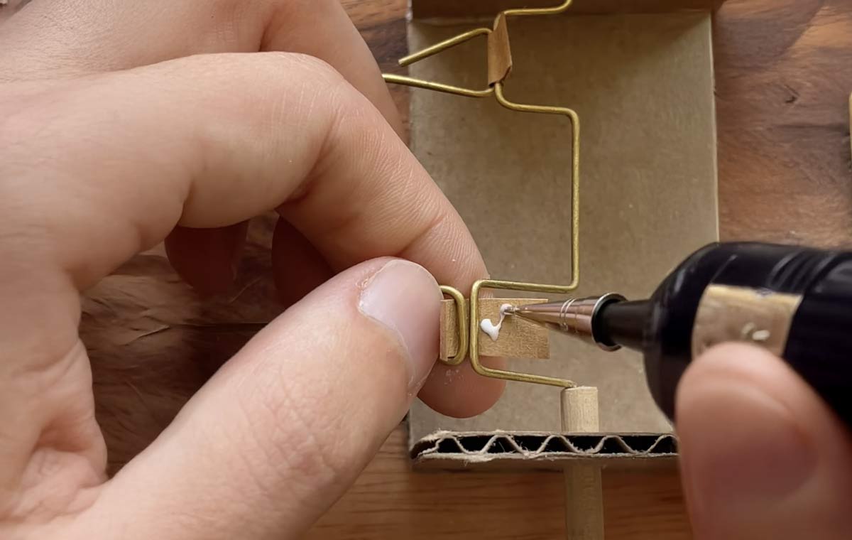 kinetic-sculpture Close-up of hands assembling a small kinetic sculpture with wire, cardboard, and glue.