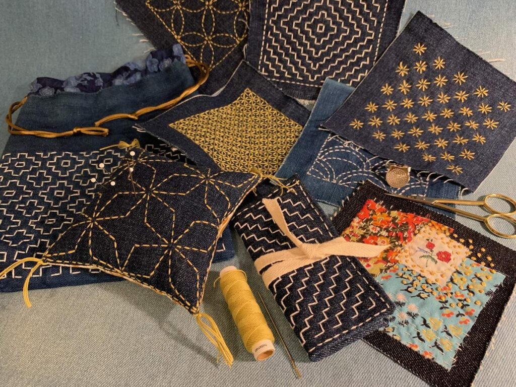 Collection of indigo fabric swatches with gold geometric hand stitching.
