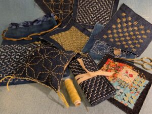 Collection of indigo fabric swatches with gold geometric hand stitching.