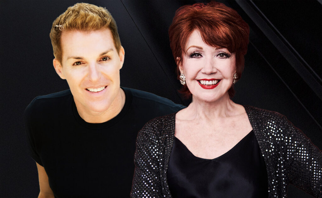 A smiling man and woman pose together against a sleek dark background. The man wears a simple black shirt, and the woman wears a sparkling black sequined jacket over a satin top, with red hair and bright lipstick. The warm, elegant portrait conveys a sense of glamour and partnership.