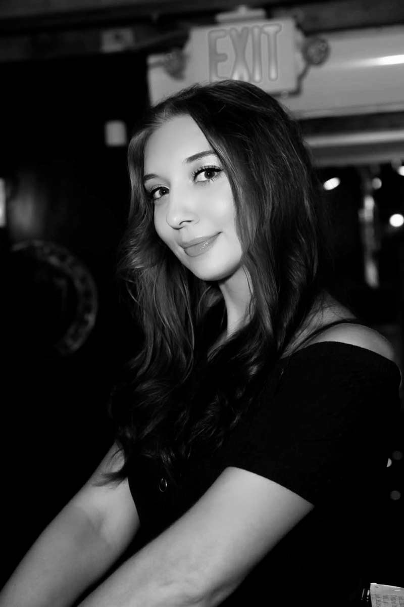 Black-and-white headshot of woman with long hair, softly smiling indoors
