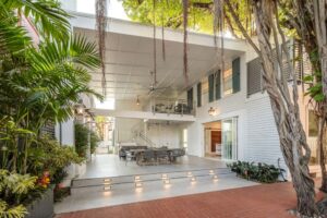 Open-air courtyard at the PEAR House with tropical landscaping, a large banyan tree, and covered seating beneath the artist residence.
